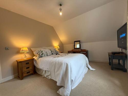 a bedroom with a bed and a flat screen tv at Charming Detached Cottage Guest Room in Silsoe Village in Bedford