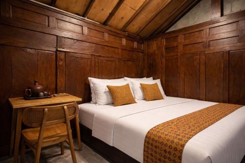 a bedroom with a bed and a wooden wall at Dapur Alit Villas in Yogyakarta
