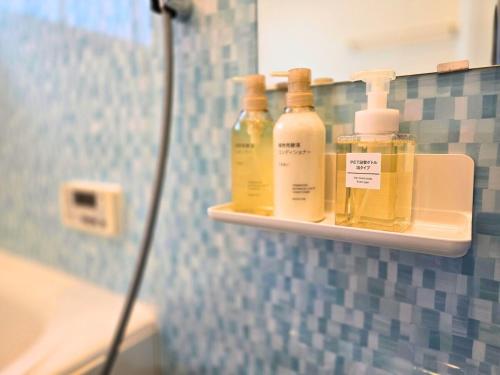 a shelf with four bottles of soap on it in a bathroom at sora in Osaka