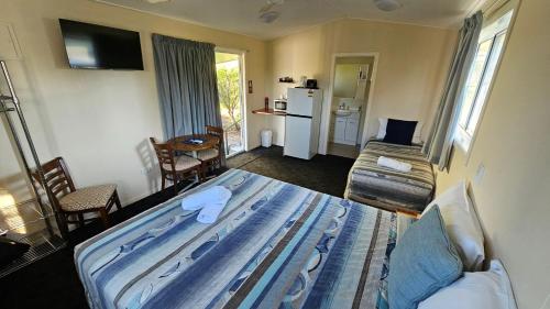 a room with a bed and a kitchen with a refrigerator at Mitchell Motel & Cabins in Mitchell