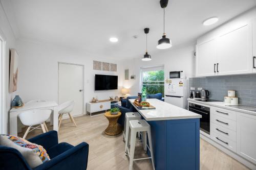 a kitchen and living room with white cabinets and a blue island at Smugglers Cove - Seaside Comfort near Dining & Shops in Victor Harbor