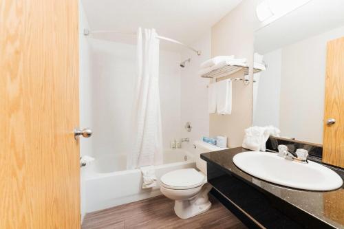 a white bathroom with a sink and a toilet at Super 8 by Wyndham Grande Prairie in Grande Prairie
