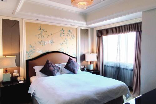 a bedroom with a large white bed with a window at Ramada Plaza Tianlu Hotel in Wuhan