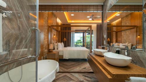 a bathroom with two sinks and a tub and a bedroom at Gardens Hill Resort & Spa in Beau Vallon