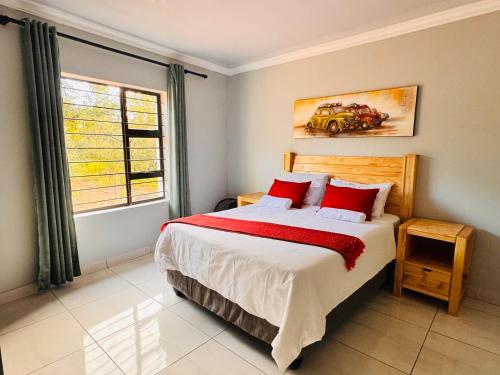 a bedroom with a bed with red pillows and a window at Unogwaja Rest in Marloth Park