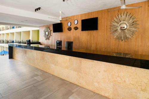 a lobby with a long counter with clocks on the wall at Decameron Isla Coral Guayabitos, Ramada All-Inclusive Resort in Rincon de Guayabitos