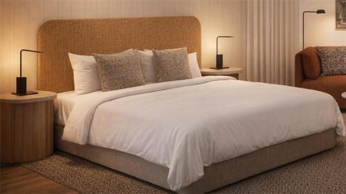 a bedroom with a large white bed and a chair at Quest Goulburn North in Goulburn