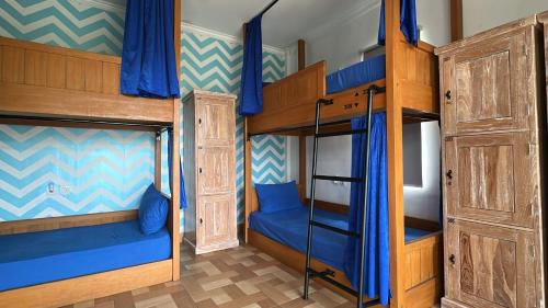 two bunk beds in a room with blue curtains at Beach Hut Hostel in Kuta