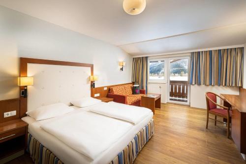 a hotel room with a bed and a desk at KUHOTEL Steinplatte, Trademark Collection by Wyndham in Waidring