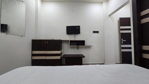a bedroom with a bed and a desk and a tv at SHRI DIVYAM Hotel & Restaurant in Bhopal