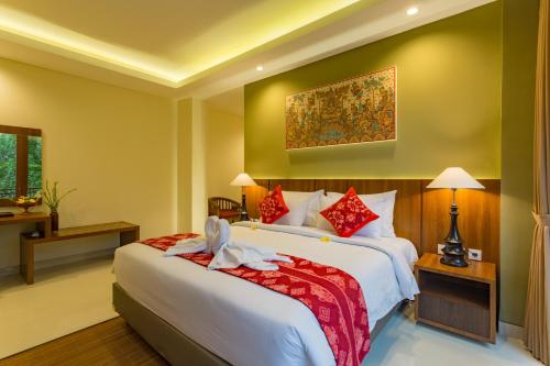 a bedroom with a large bed with red pillows at River Sakti Ubud by Prasi in Ubud