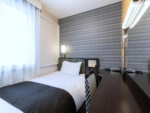a hotel room with a bed and a window at APA Hotel Sapporo Susukino Ekimae in Sapporo