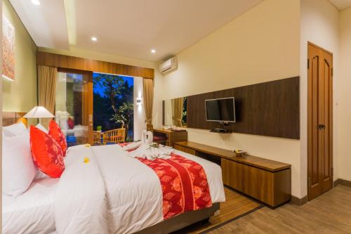 a bedroom with a large bed and a television at River Sakti Ubud by Prasi in Ubud