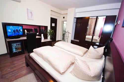 a bedroom with a large bed and a television at Hotel Poarta Transilvaniei in Bistriţa