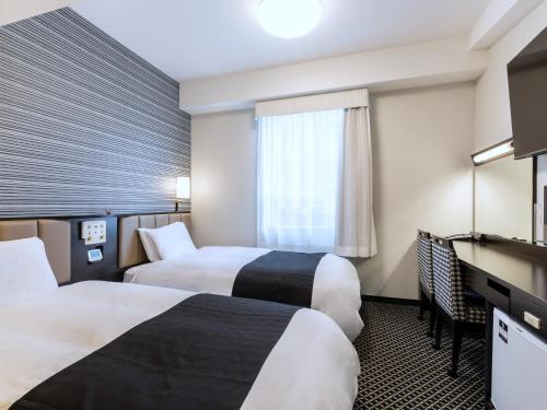 a hotel room with two beds and a television at APA Hotel Sapporo Susukino Ekimae in Sapporo