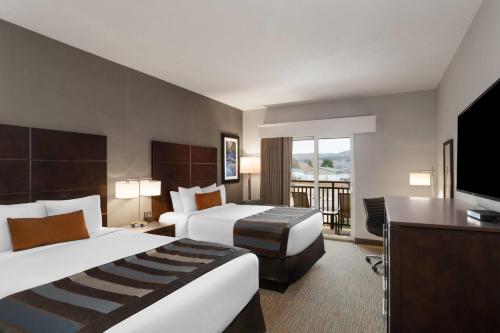 a hotel room with two beds and a flat screen tv at Wingate by Wyndham Hurricane Zion National Park in Hurricane