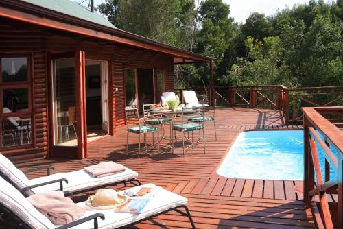 a deck with chairs and a swimming pool next to a cabin at The Fernery Lodge & Chalets in Stormsrivier