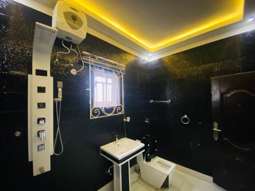a black bathroom with a sink and a toilet at Gustavó Premium Apartment in Benin City