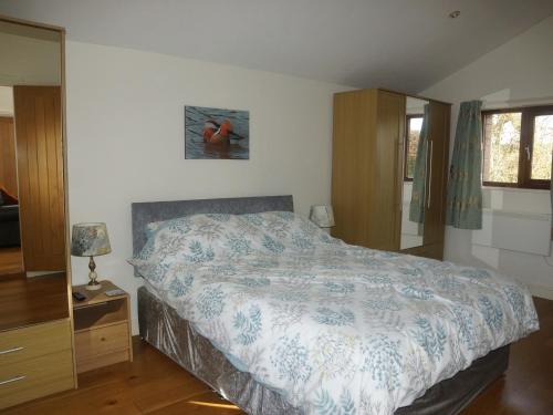 a bedroom with a bed with a blue and white comforter at Dilly Dally Barn in Holsworthy