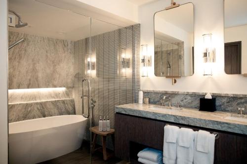 a bathroom with a tub and a sink and a tub and a mirror at Riverplace Hotel in Portland