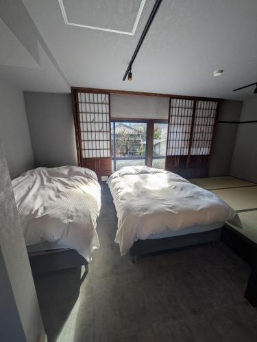 two twin beds in a room with windows at 川まで徒歩1分川沿いにある一軒宿あせみ in Nakajima