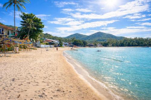 a beach with a group of people in the water at Beachfront 4BR Villa with Private Pool - Ocean Access in Chaloklum