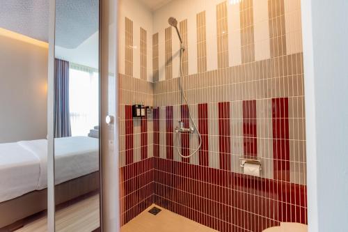 a bathroom with a shower with red tile at Azana Boutique Hotel Solo in Purwosari