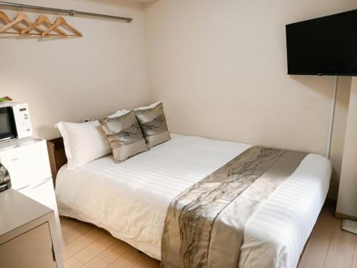 a bedroom with a white bed with a tv on the wall at コーポラス十日市 - supported by COCOSTAY in Hiroshima