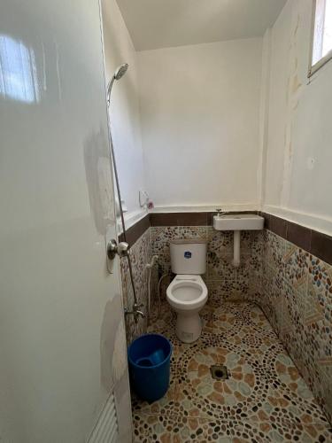 a small bathroom with a toilet and a tiled floor at Little John's Town Inn in Coron