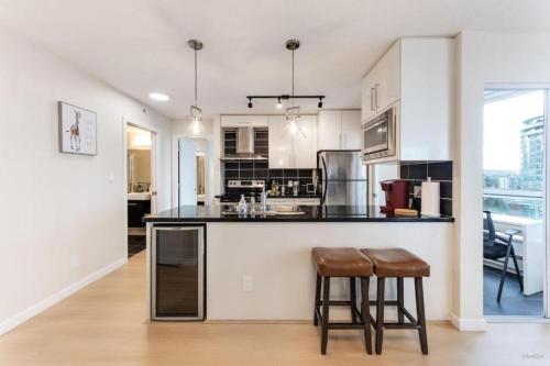 a kitchen with white cabinets and a black counter top at BC Place & Rogers Arena Downtown Modern Condo in Vancouver