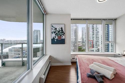 a bedroom with large windows and a bed with a pink blanket at BC Place & Rogers Arena Downtown Modern Condo in Vancouver