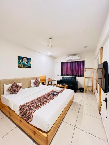a bedroom with a large bed and a tv at Hotel Royal Manor in Rajkot