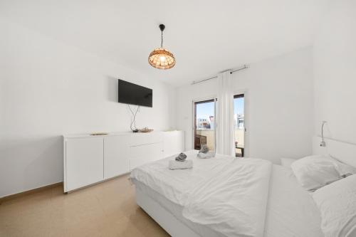 a white bedroom with a bed and a tv at Villa Ella in Eilat