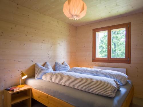 a bed in a wooden room with a window at Labbrunnu OG in den Walliser Alpen in Rosswald
