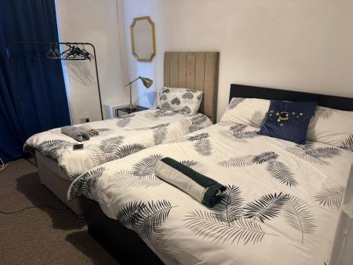 two twin beds in a bedroom with a bedspread with palm leaves at ThinkGlobal Properties Ltd in Stoke on Trent