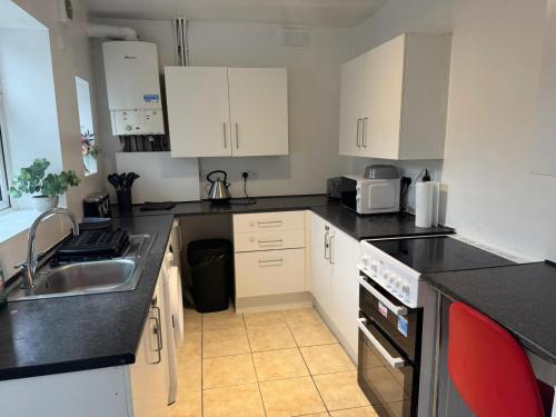 a kitchen with white cabinets and black counter tops at ThinkGlobal Properties Ltd in Stoke on Trent
