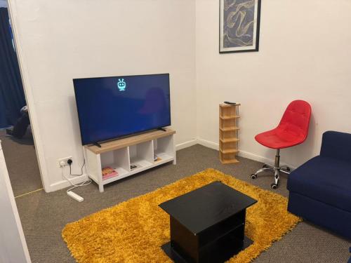 a living room with a tv and a red chair at ThinkGlobal Properties Ltd in Stoke on Trent