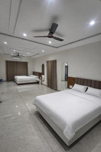 a bedroom with two beds and a ceiling fan at Hotel Abhishek Pride Shani Shinganapur in Godhegaon