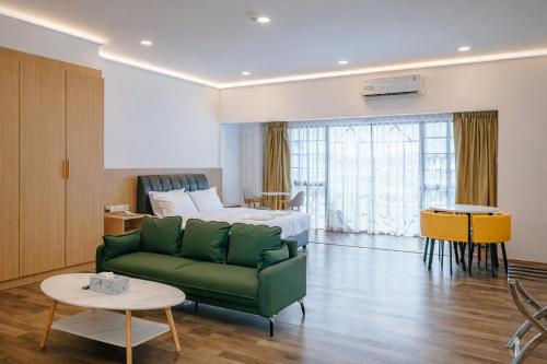 a living room with a green couch and a bed at Hotel Koperasi in Seria