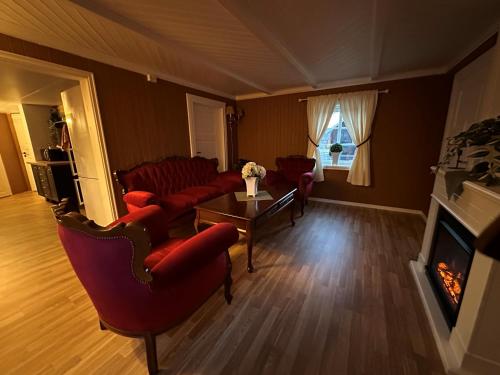 a living room with red furniture and a fireplace at Låven Parsellhage in Hoset