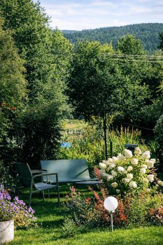 a garden with a bench and flowers in the grass at Dom na Przedgórzu-Spokojny pobyt blisko górskich tras in Świeradów-Zdrój