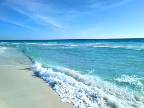a wave breaking on a beach with the ocean at Gulf Balcony - Boutique Comforts & 2 King Suites in Fort Walton Beach