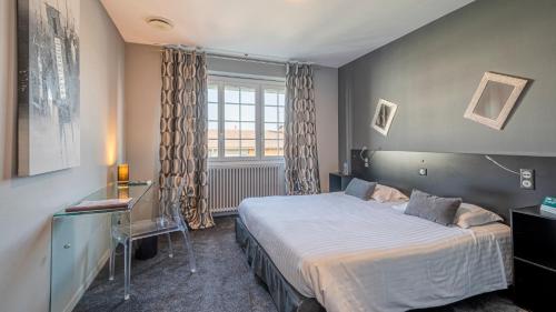 une chambre avec un lit, un bureau et une fenêtre dans l'établissement Logis La Thomasse, à Aurillac