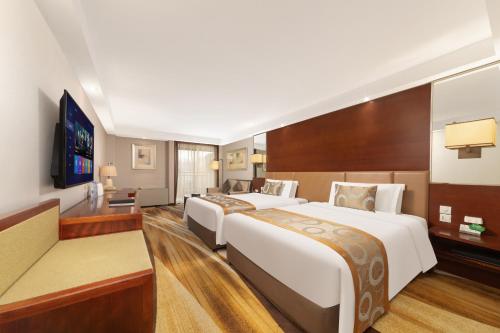 a hotel room with two beds and a flat screen tv at Jianguo Hotel Xi'an in Xi'an