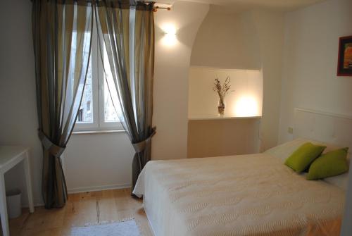 een slaapkamer met een bed met groene kussens en een raam bij Rooms Piazzetta in Cres
