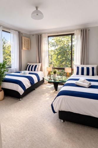 a bedroom with two beds and a glass table at Blue Mountains charm with Spa! in Wentworth Falls
