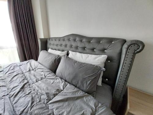 a gray bed with pillows on it in a bedroom at PoolView Condo Near MRT, Nice & Quiet, speedy net in Bangkok