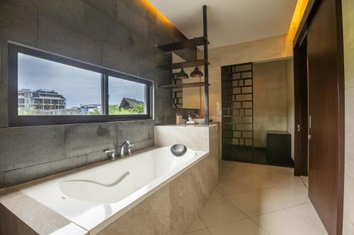 a bathroom with a bath tub and a window at La Paradis Villa in Canggu