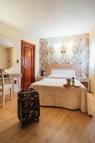 a hotel room with a bed and a suitcase at Hostal Cortés in Cuenca