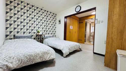 a bedroom with two beds and a clock on the wall at サンハウス 2 in Osaka